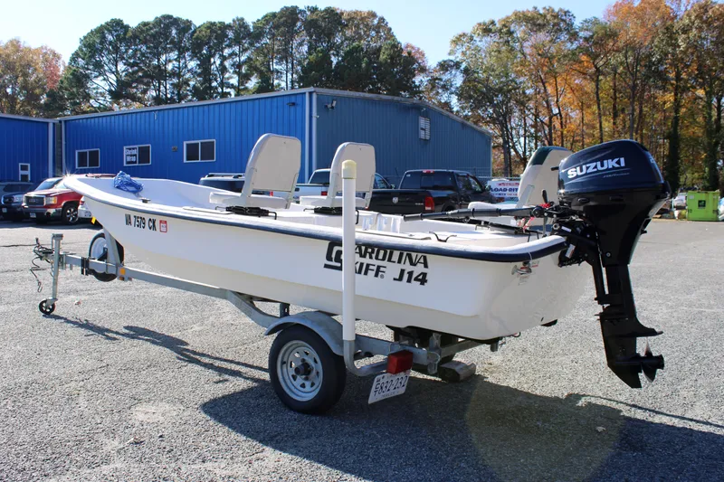 Slide: The Image of 2015 Carolina Skiff J14 CC boat with Suzuki motor on trailer, parked outdoors. - 3