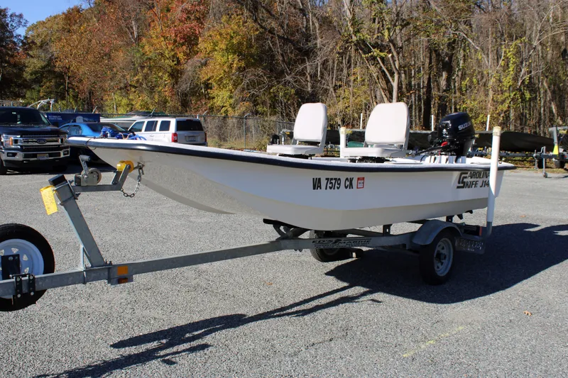 Slide: The Image of 2015 Carolina Skiff J14 CC boat on trailer in parking lot, surrounded by autumn trees. - 5