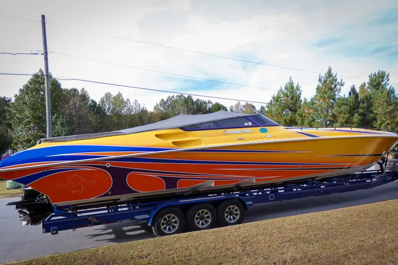 Slide: The Image of 2006 Fountain 47 Lightning speedboat with vibrant orange and blue design on a trailer. - 2