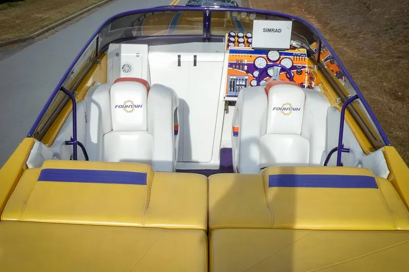 Slide: The Image of 2006 Fountain 47 Lightning boat interior with vibrant yellow and purple seating and dashboard. - 8