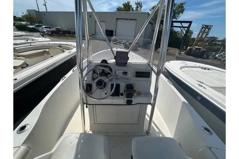 Slide: The Image of 2002 Sailfish 216 CC boat cockpit with steering wheel and controls, docked outdoors. - 6
