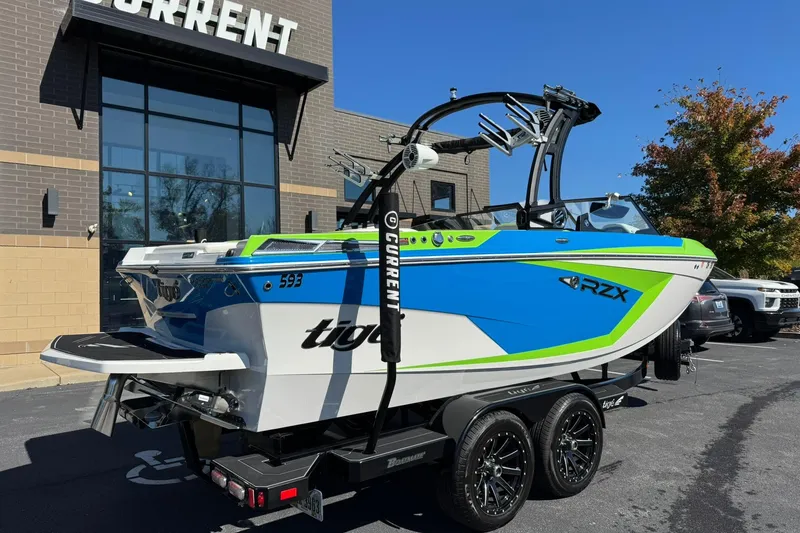 Slide: The Image of 2022 Tigé 20RZX boat in vibrant blue and green, parked outside a building. - 3