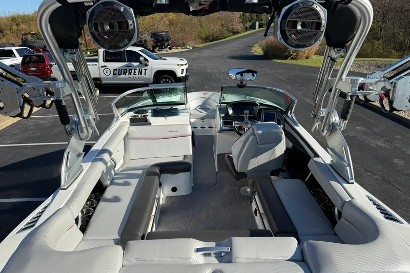 Slide: The Image of 2018 MasterCraft XT21 boat interior with seating and audio system, parked outdoors. - 14