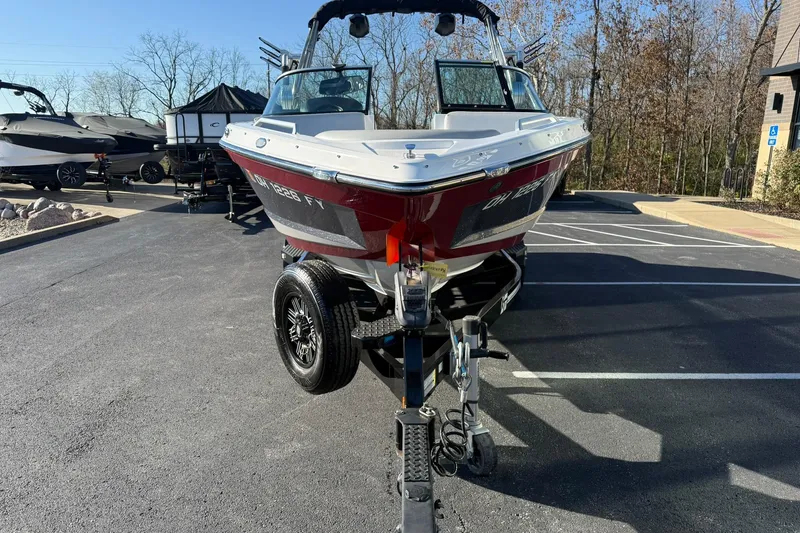 Slide: The Image of 2018 MasterCraft XT21 boat on trailer in parking lot, surrounded by trees. - 8