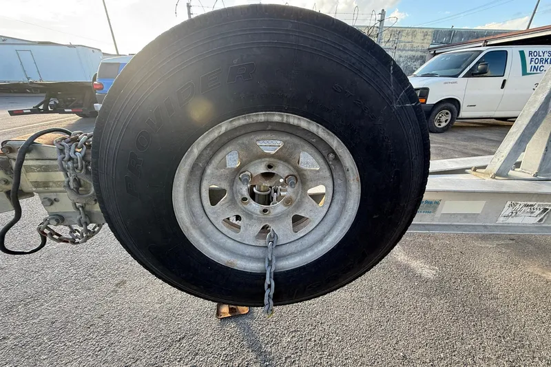 Slide: The Image of Trailer wheel with chain on a Contender 35 Express, 1998 model, in a parking lot. - 101