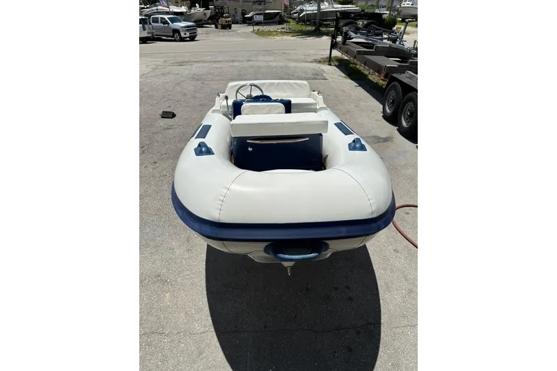 Slide: The Image of 2020 Ribjet 10 inflatable boat with white and blue design, parked outdoors. - 2