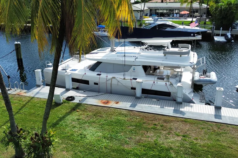 Slide: The Image of 2021 Leopard 45 catamaran docked by palm trees, featuring spacious deck and modern design. - 12