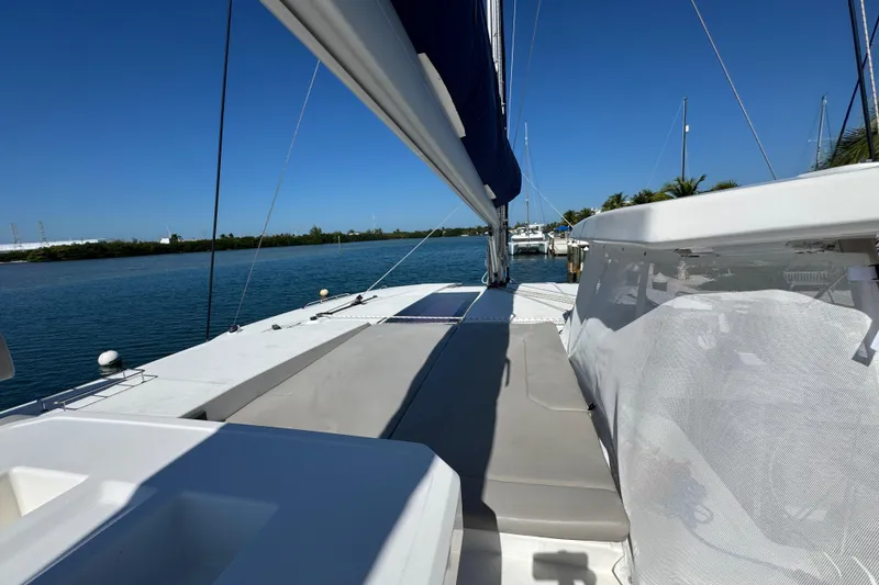 Slide: The Image of 2021 Leopard 45 catamaran deck with sunbathing area, docked by calm waters. - 51