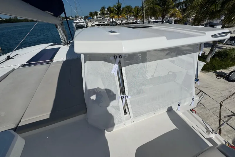Slide: The Image of 2021 Leopard 45 catamaran deck with sunshade, docked near palm trees. - 52