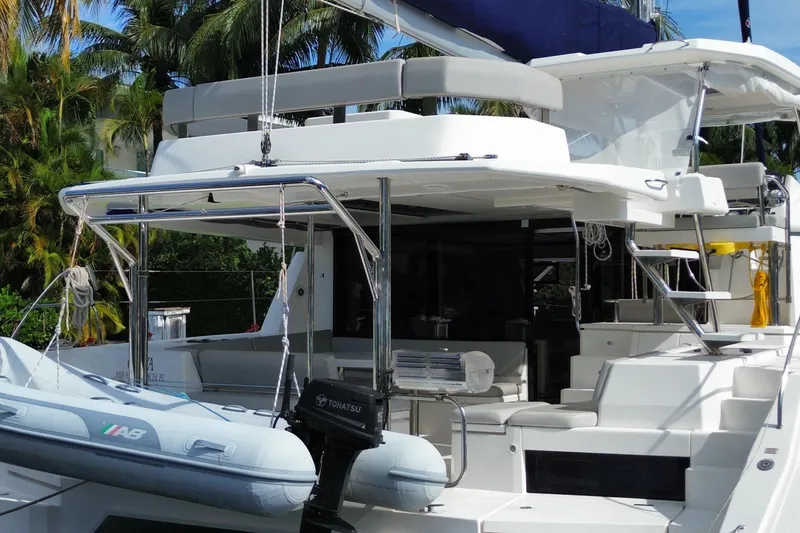 Slide: The Image of 2021 Leopard 45 catamaran with dinghy, docked near lush tropical foliage. - 6