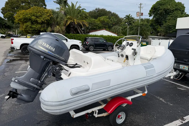 The Image of Inflatable Caribe 12 boat with Yamaha motor on trailer, parked outdoors. - 0