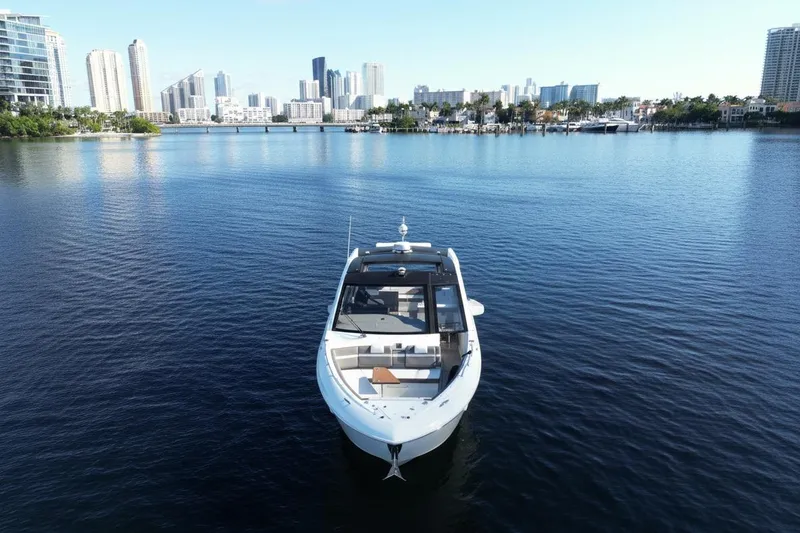 Slide: The Image of 2021 Cruisers Yachts 42 GLS OB on calm water with city skyline backdrop. - 2