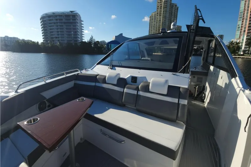 Slide: The Image of 2021 Cruisers Yachts 42 GLS OB interior with seating and table, docked by waterfront buildings. - 23