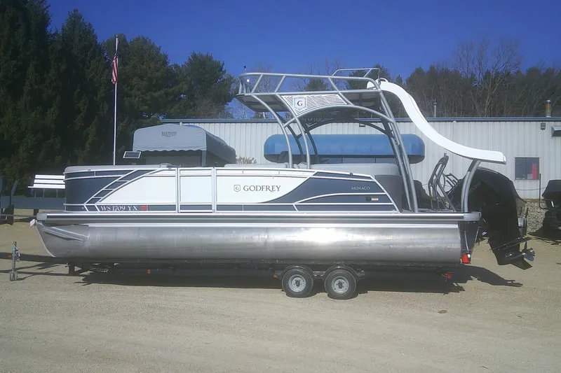 The Image of 2024 Godfrey Monaco 255 SD pontoon boat with slide, parked on a trailer. - 0