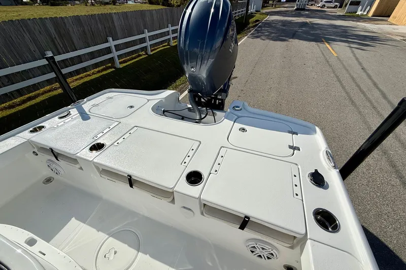 Slide: The Image of 2026 Sea Hunt BX 22 BR boat deck with storage compartments and motor, parked on street. - 8