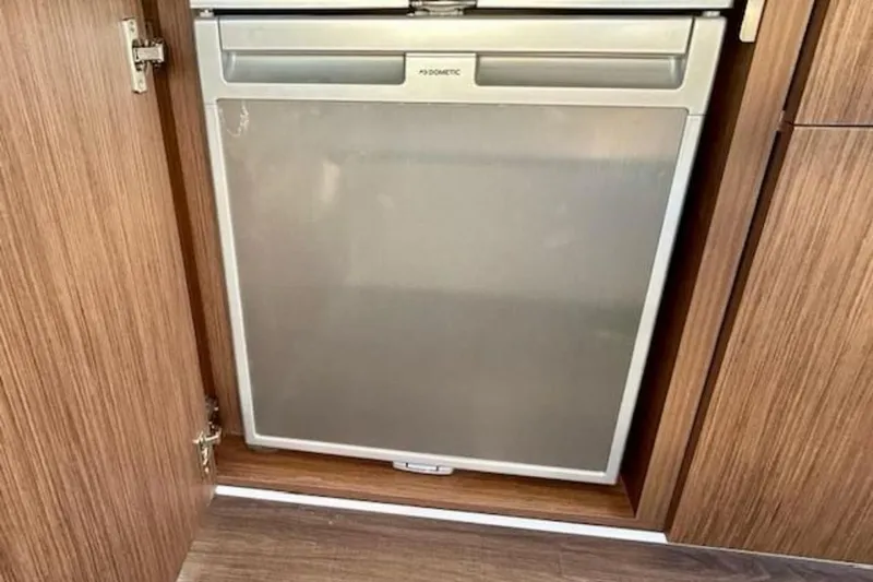 Slide: The Image of Built-in refrigerator on 2024 Beneteau Antares 9 boat, featuring wooden cabinetry. - 10