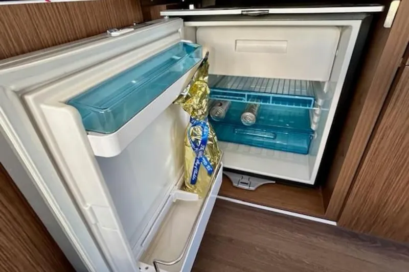 Slide: The Image of Compact refrigerator inside 2024 Beneteau Antares 9 boat, featuring drinks and storage. - 11