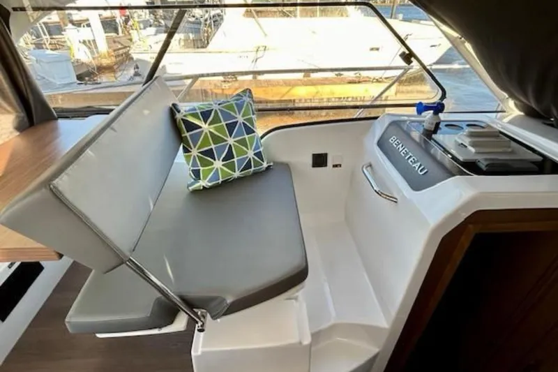 Slide: The Image of Interior of 2024 Beneteau Antares 9 with cushioned seating and geometric pillow. - 6