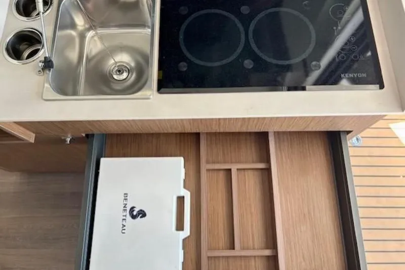 Slide: The Image of 2024 Beneteau Antares 9 kitchen with sink, stove, and storage drawer. - 9