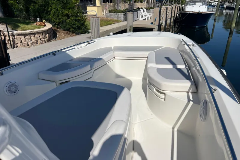 Slide: The Image of 2015 Boston Whaler 270 Dauntless boat interior with cushioned seating and dockside view. - 13