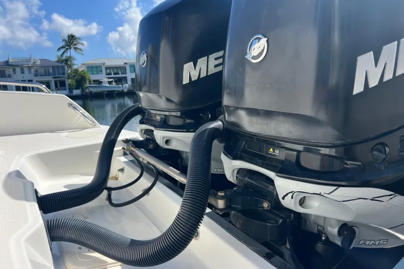 Slide: The Image of Twin Mercury outboard engines on a 2015 Boston Whaler 270 Dauntless boat, docked by waterfront homes. - 7