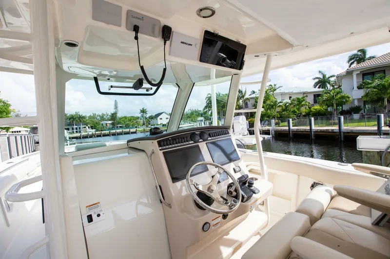 Slide: The Image of 2023 Boston Whaler 380 Outrage helm with modern controls and waterfront view. - 10