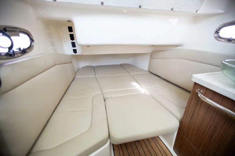 Slide: The Image of 2023 Boston Whaler 380 Outrage cabin interior with beige seating and wooden accents. - 13