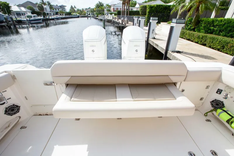 Slide: The Image of 2023 Boston Whaler 380 Outrage boat with foldable seating, docked in a serene canal setting. - 3