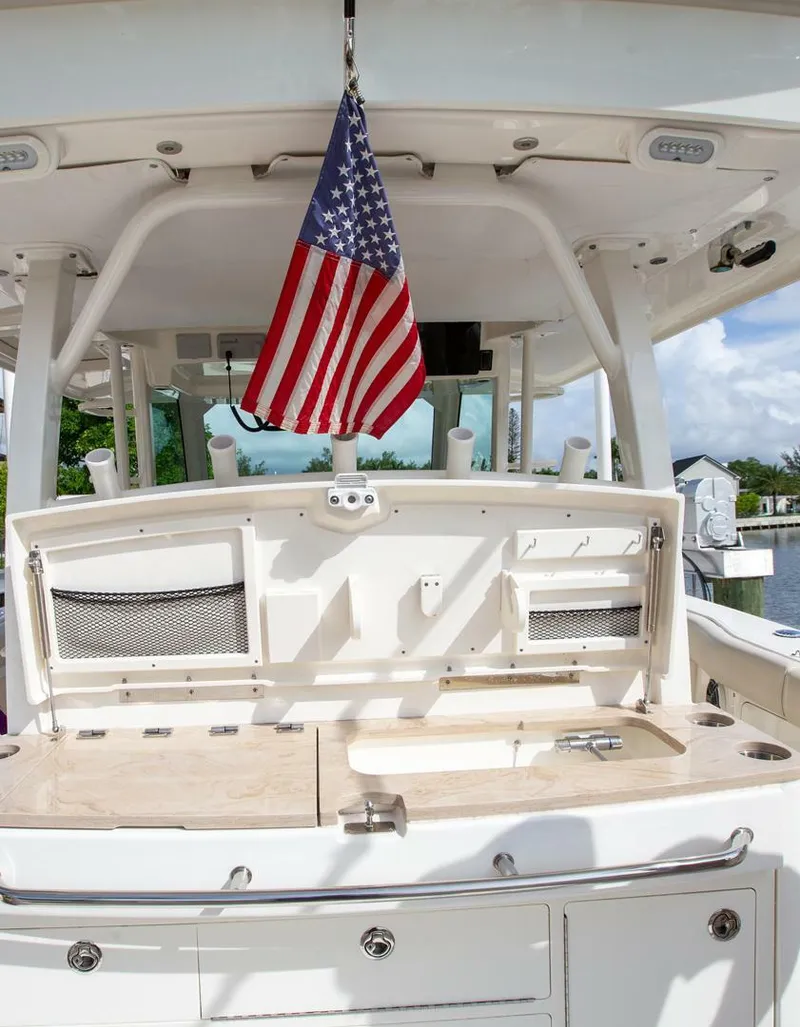 Slide: The Image of 2023 Boston Whaler 380 Outrage boat with American flag, featuring a well-equipped cockpit. - 6