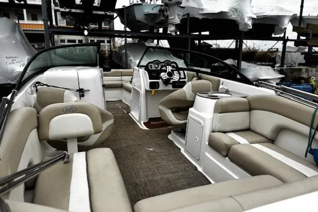 Slide: The Image of 2018 NauticStar 243DC Sport Deck boat interior with beige seating and modern dashboard. - 17