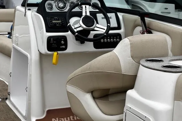 Slide: The Image of 2018 NauticStar 243DC Sport Deck boat interior with steering wheel and beige seating. - 18