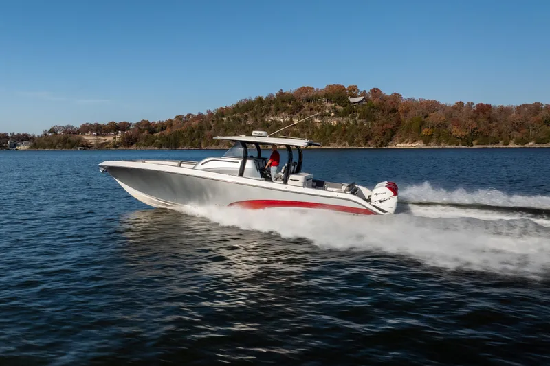 The Image of 2020 Fountain 43 NX boat cruising on a lake with scenic autumn backdrop. - 1