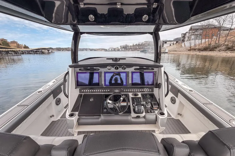 Slide: The Image of Cockpit view of 2020 Fountain 43 NX boat with advanced navigation systems on a serene lake. - 38