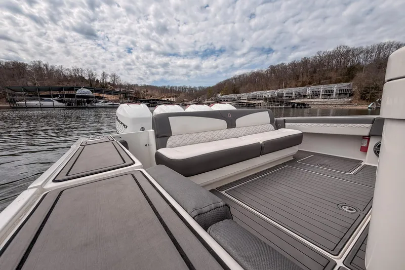 Slide: The Image of 2020 Fountain 43 NX boat interior with seating, docked by a scenic lakeside. - 46