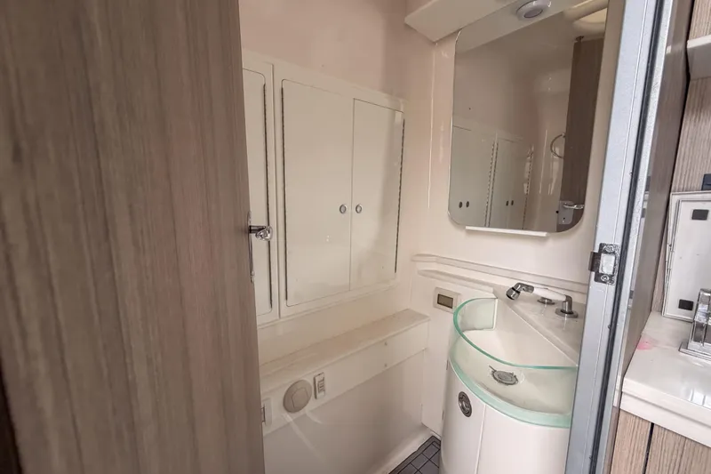 Slide: The Image of Compact bathroom in a 2020 Fountain 43 NX boat, featuring modern fixtures and storage cabinets. - 54