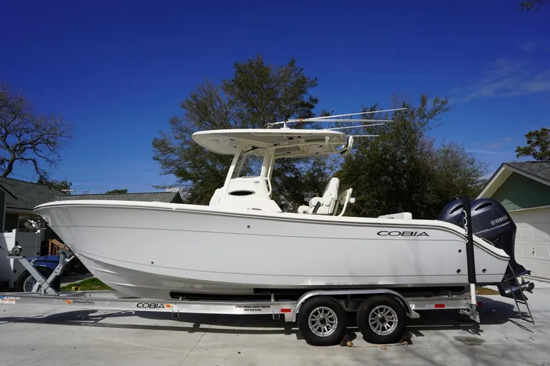 The Image of 2022 Cobia 266 boat on trailer, parked outdoors under clear blue sky. - 1