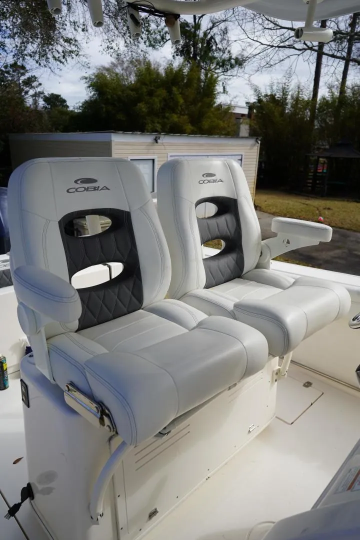 Slide: The Image of 2022 Cobia 266 boat seats with white and black upholstery, outdoor setting. - 11