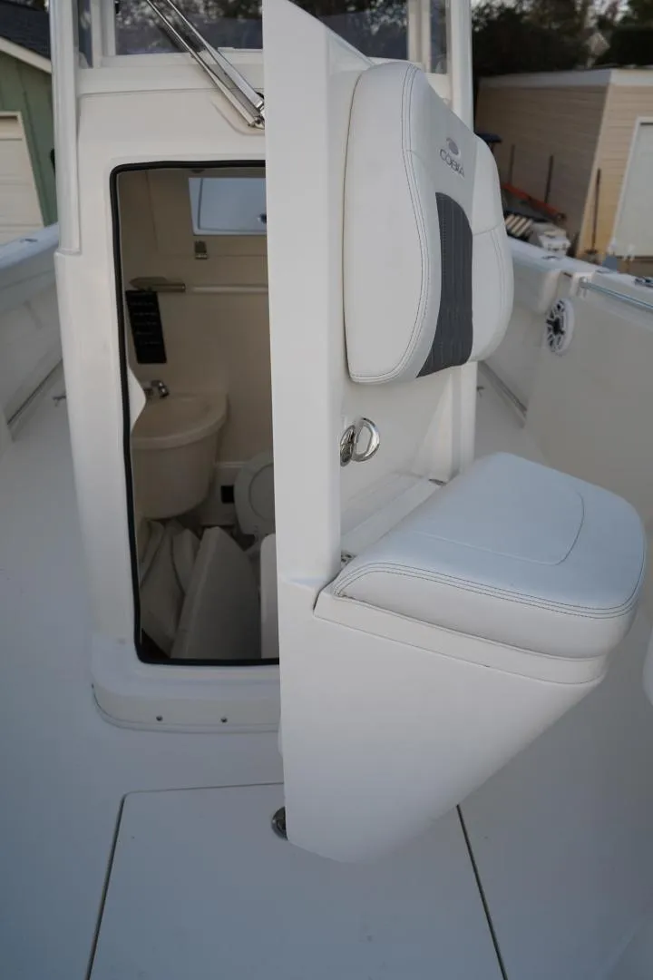 Slide: The Image of 2022 Cobia 266 boat interior with open cabin door and cushioned seating. - 22
