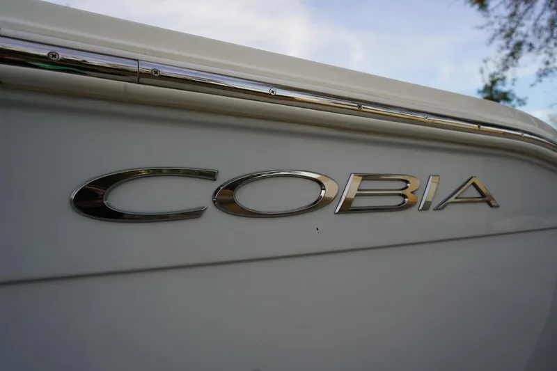 Slide: The Image of 2022 Cobia 266 boat logo on white hull with chrome detailing. - 27