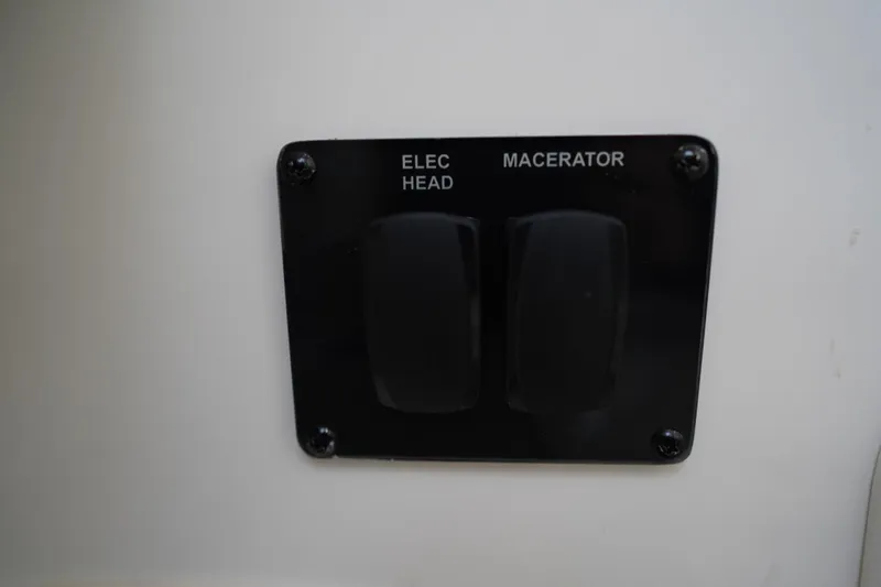 Slide: The Image of Control panel with switches for electric head and macerator on 2022 Cobia 266 boat. - 38