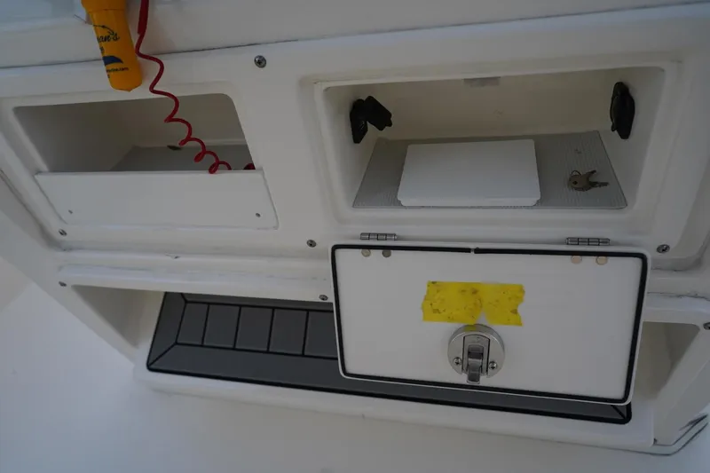 Slide: The Image of 2022 Cobia 266 boat storage compartments with keys and safety equipment. - 39