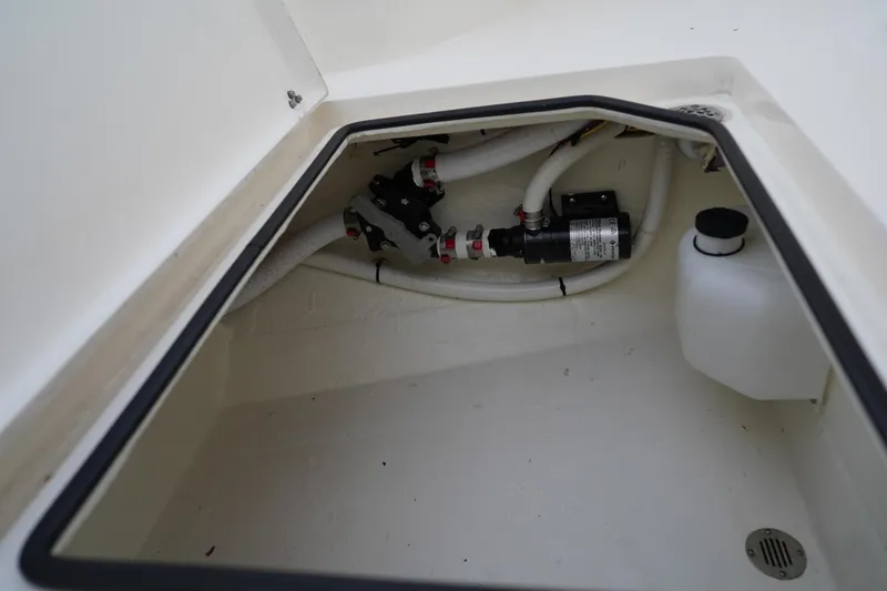 Slide: The Image of 2022 Cobia 266 boat storage compartment with plumbing and pump system. - 43