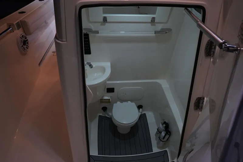 Slide: The Image of 2022 Cobia 266 boat interior with compact bathroom, featuring toilet and sink. - 47