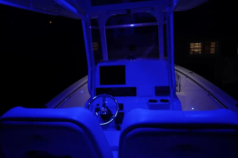 Slide: The Image of 2022 Cobia 266 boat interior illuminated with blue lighting at night. - 48