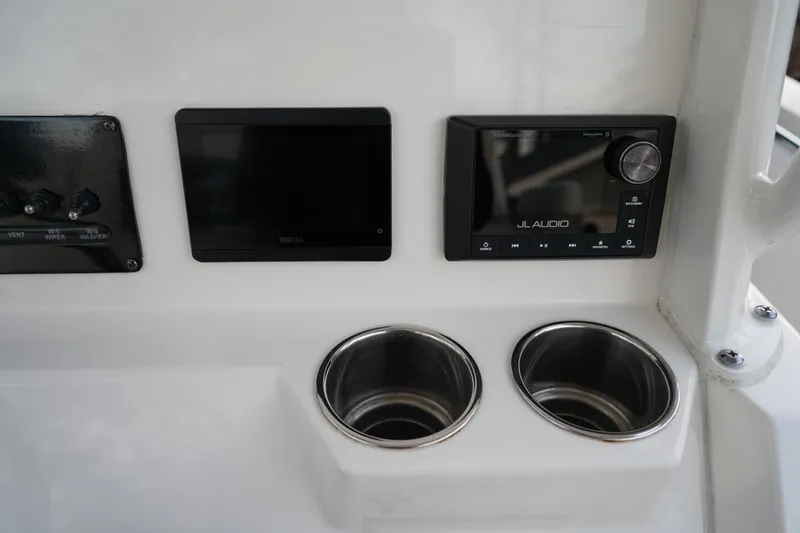 Slide: The Image of Control panel of 2022 Cobia 266 boat with audio system and cup holders. - 7