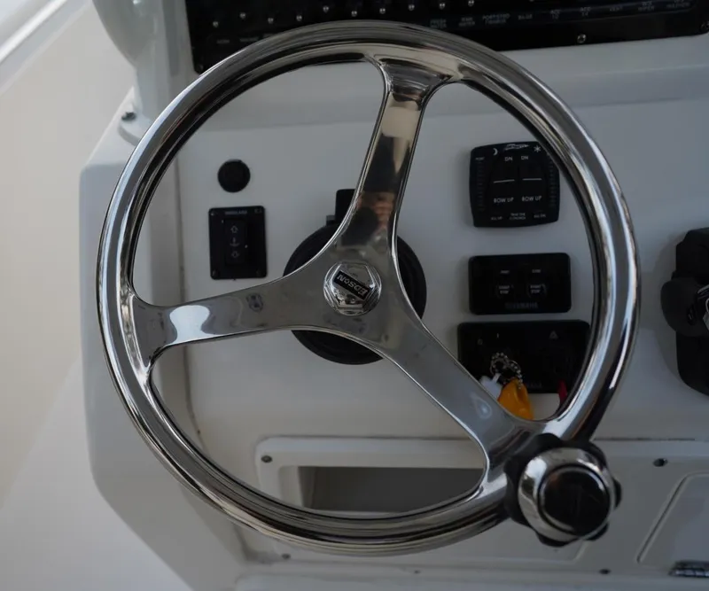 Slide: The Image of Steering wheel of a 2022 Cobia 266 boat, featuring a sleek chrome finish. - 8