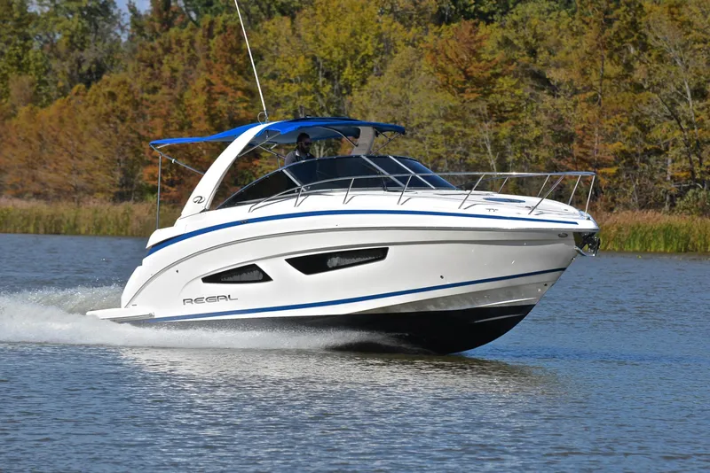 The Image of 2018 Regal 33 Express boat cruising on a serene lake with forest backdrop. - 1