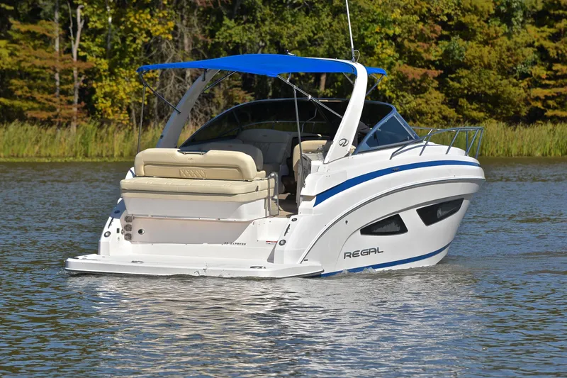 Slide: The Image of 2018 Regal 33 Express boat with blue canopy on a serene lake. - 11
