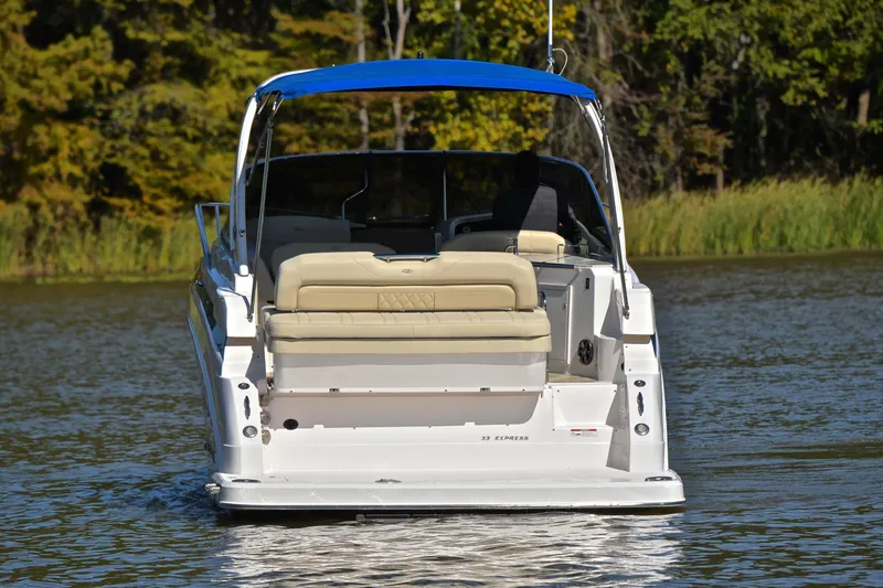 Slide: The Image of 2018 Regal 33 Express boat on a calm lake with lush green background. - 12