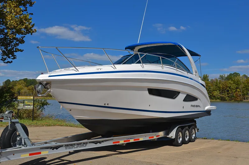 Slide: The Image of 2018 Regal 33 Express boat on trailer by a lake under clear blue sky. - 13